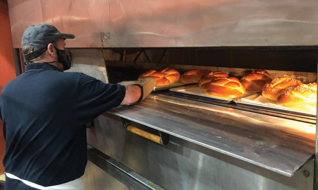 Man at Dakota Break Company checking bread in the oven