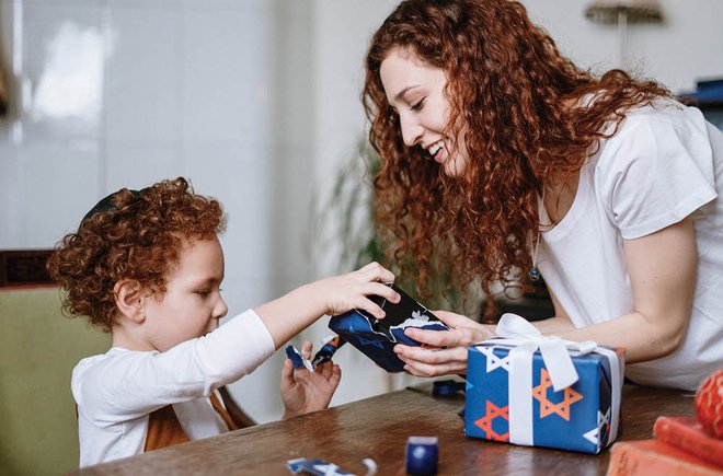 Woman helping a young child unwrap a present