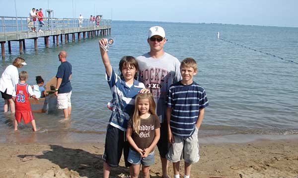 A family standing on a beach in front of a pier