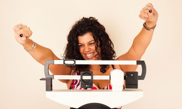 Happy woman on scale with arms in the air