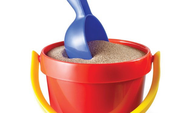 A red bucket full of sand with a purple shovel in it