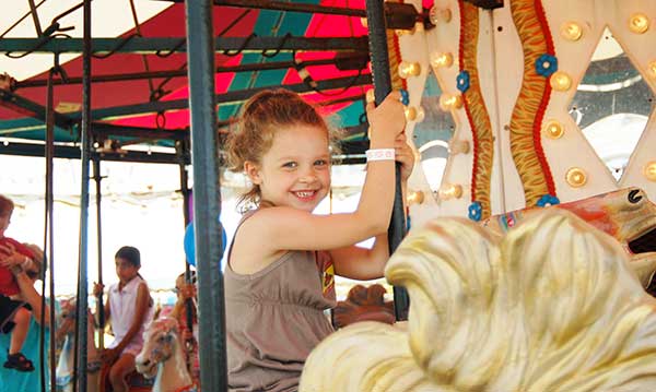 Little girl smiles as she rides a carousel