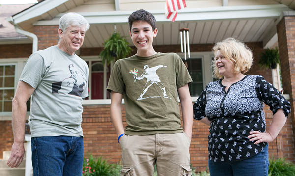 Man and woman with a foreign exchange student standing in front of brick house