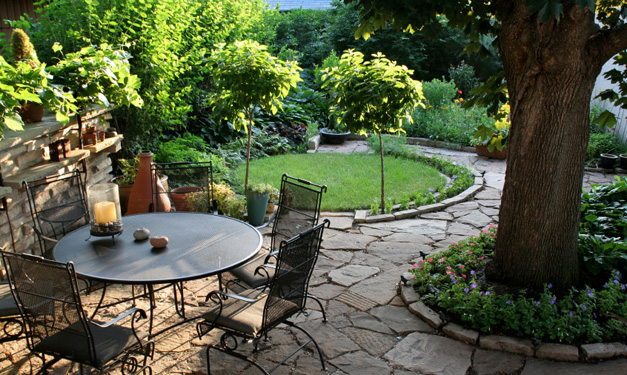 Tree-filled backyard with a patio set and stone pavers