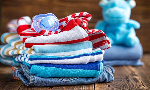 Stack of kids clothes with a pacifier on top