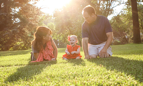 Family of three sitting in a park on a sunny day