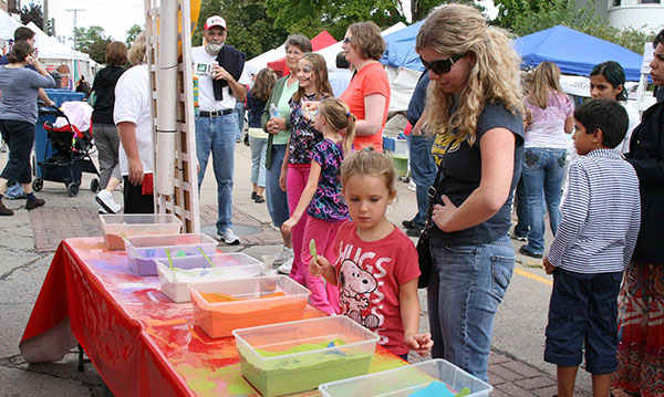 Little girl standing in front of colorful sand in clear boxes