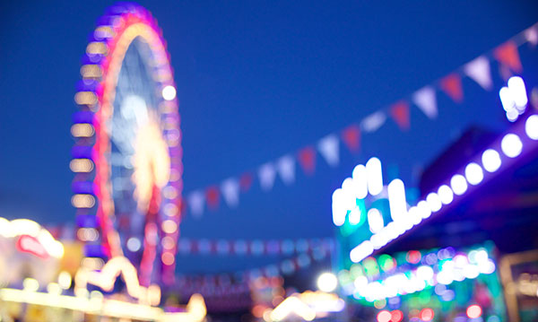 A blurry ferris wheel and colorful lights on a dark blue background