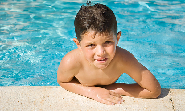 Little boy climbing out of a pool