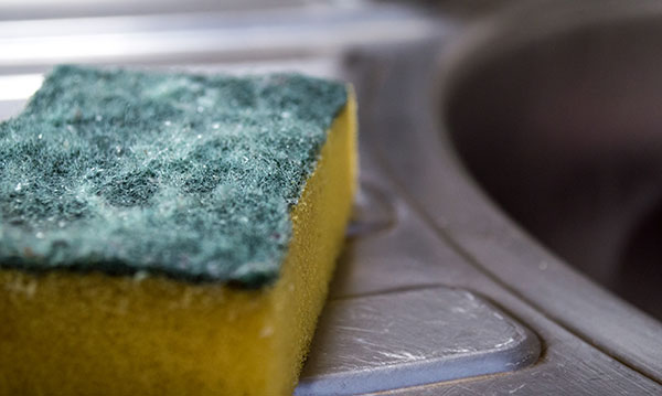 Dirty sponge sitting on a counter next to the sink