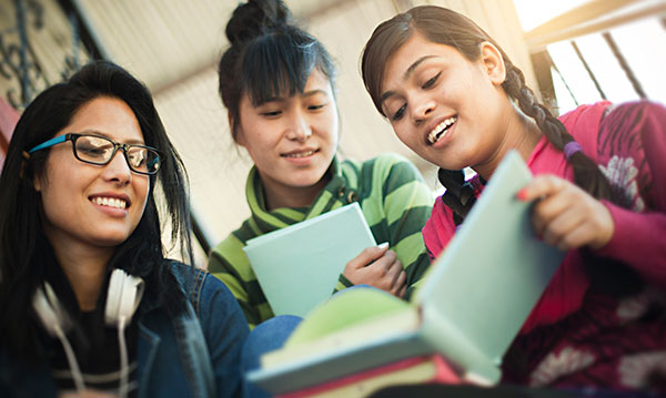 Three teen girls looking at a book