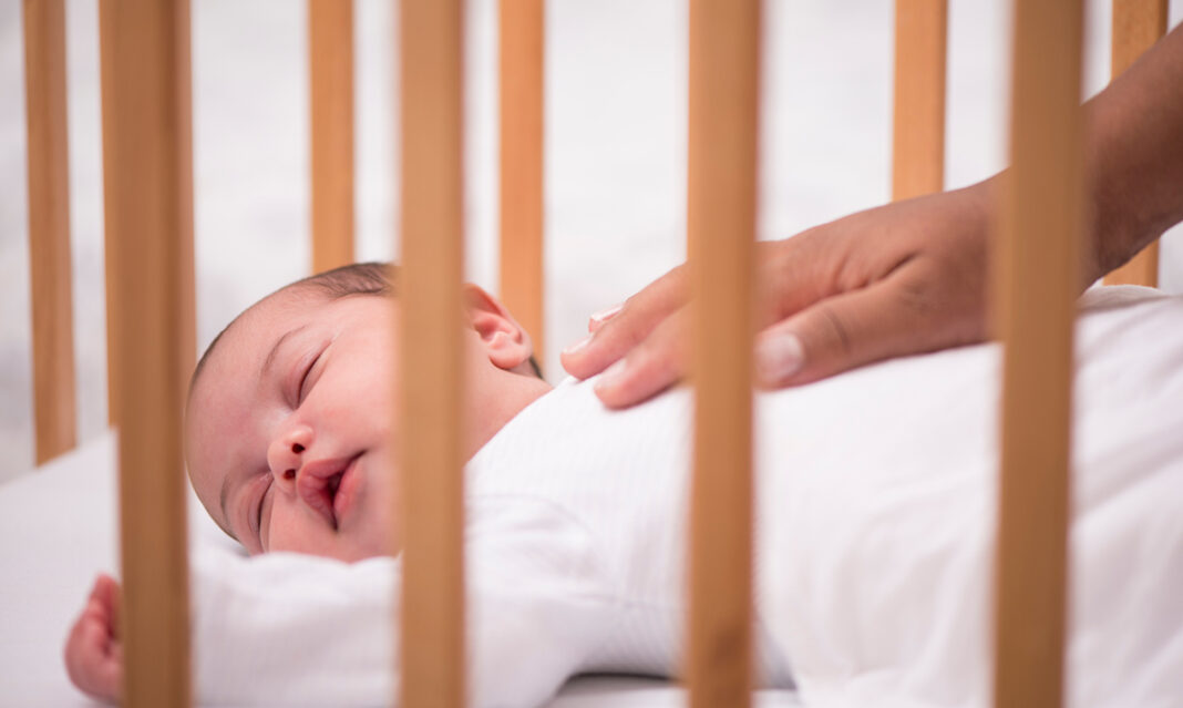 safe-sleep-new-guidelines-baby-in-crib-with-parent-soothing