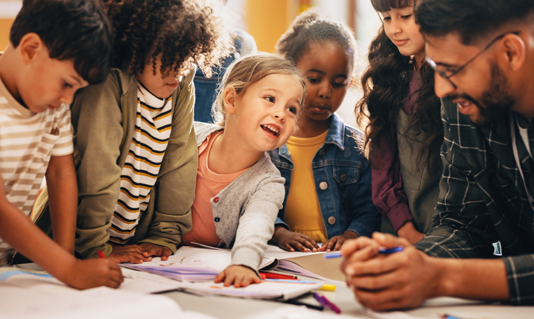 Teacher engaging with a diverse group of elementary students during a classroom activity, illustrating inclusive support and autism accommodations at school.