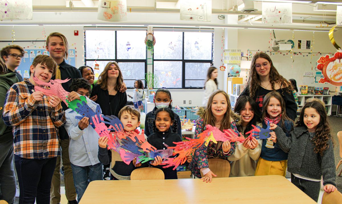 Students at The Roeper School proudly display a collaborative dragon art project during a hands-on classroom activity, highlighting the school’s creative and inclusive learning environment.