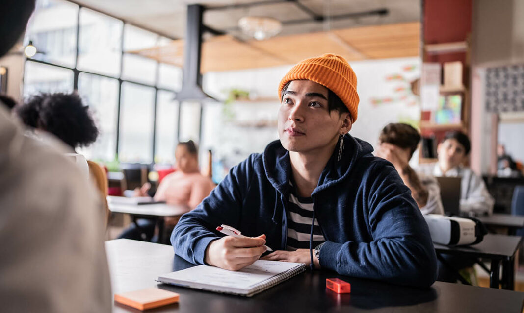 College freshman taking notes in class, focused on lecture, representing the best classes to take in college.