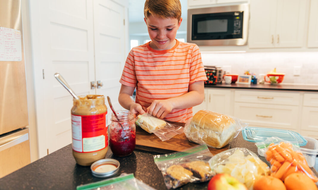 Young boy preparing school lunch developing teen life skills