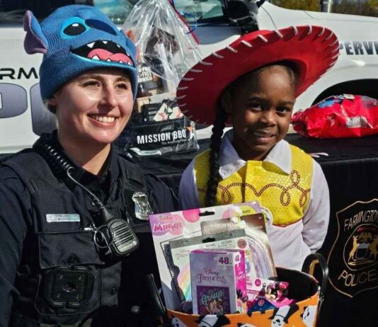Farmington Hills Police Department Trunk or Treat Farmington Hills Police officer and child in costume at trunk or treat Halloween event with candy and police car in