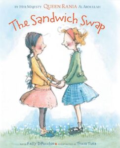 Cover of the children's book The Sandwich Swap by Queen Rania Al Abdullah and Kelly DiPucchio, illustrated by Tricia Tusa. The illustration features two young girls holding hands and smiling at each other, highlighting themes of cultural understanding, friendship, and acceptance through a story about sharing food.