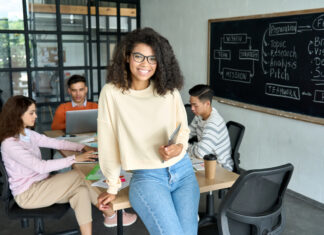 10 Reasons to Save with MESP Confident high school student smiling while working on a group project with diverse classmates in a modern classroom setting focused on teamwork and strategic planning.