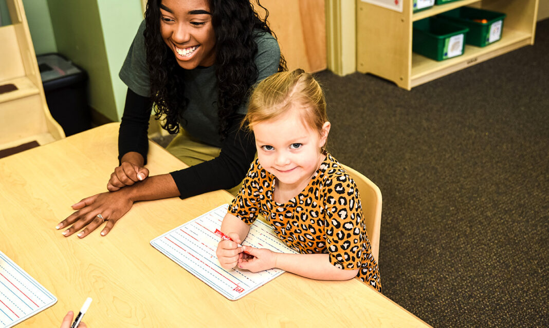kindergarten-readiness-smiling-preschooler-with-teacher-practicing-writing-skills