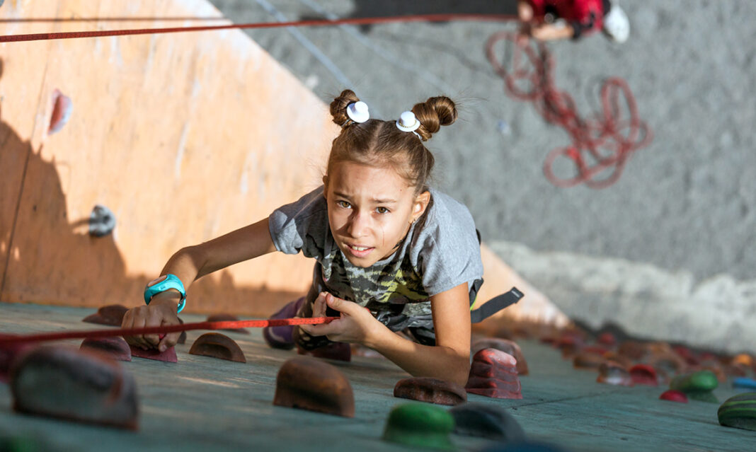 childs-strengths-girl-reaching-the-top-of-a-climbing-wall