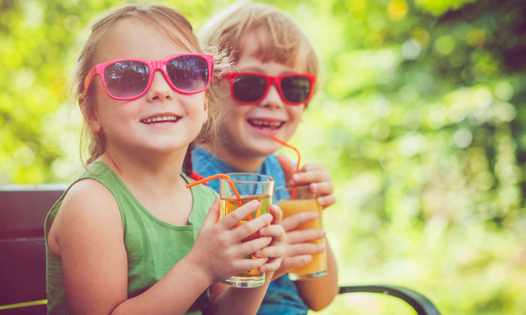 A boy and a girl holding glasses of juice with straws