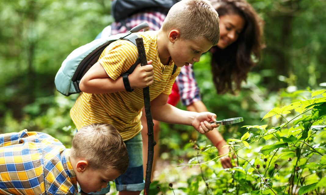 benefits-of-nature-for-autism-child-with-magnifying-glass-inspecting-nature-on-a-hike
