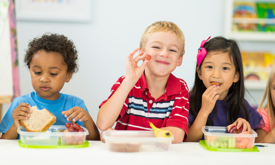 Young schoolkids eating healthy back-to-school lunches