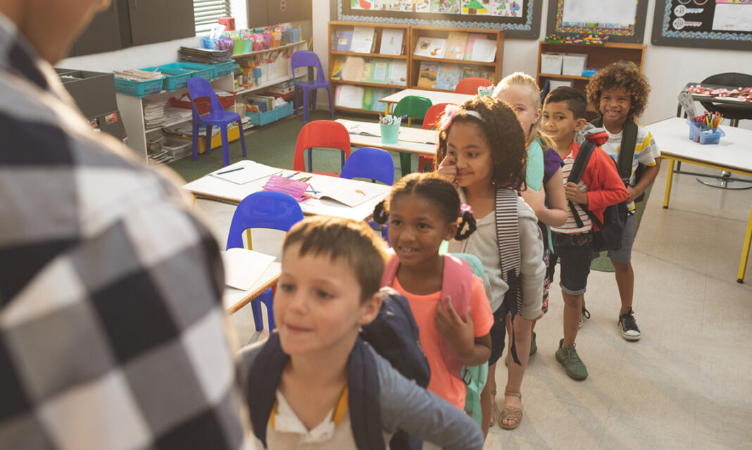 Children lining up inside a colorful classroom, preparing for school activities—an important part of school readiness for children with autism.