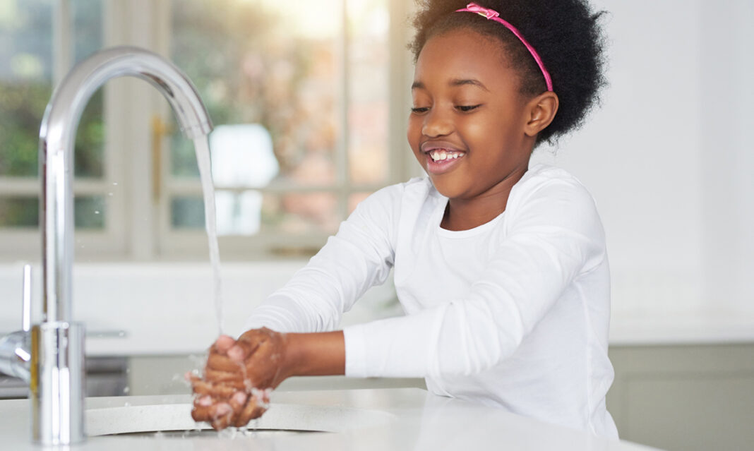 Young girl washing hands at sink