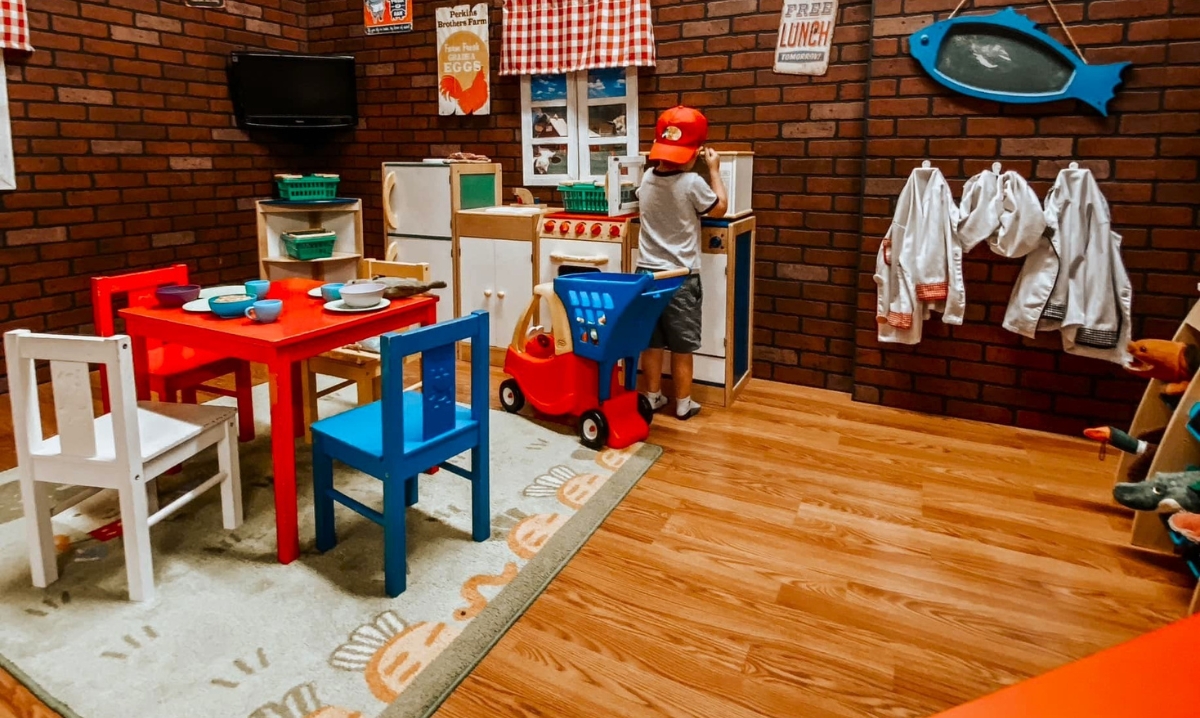 Child playing in a pretend kitchen at Boogie Babies, an indoor play place in Metro Detroit, offering creative and interactive play areas for kids.