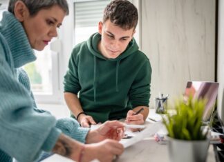 Parent and teenager reviewing college planning materials together at home
