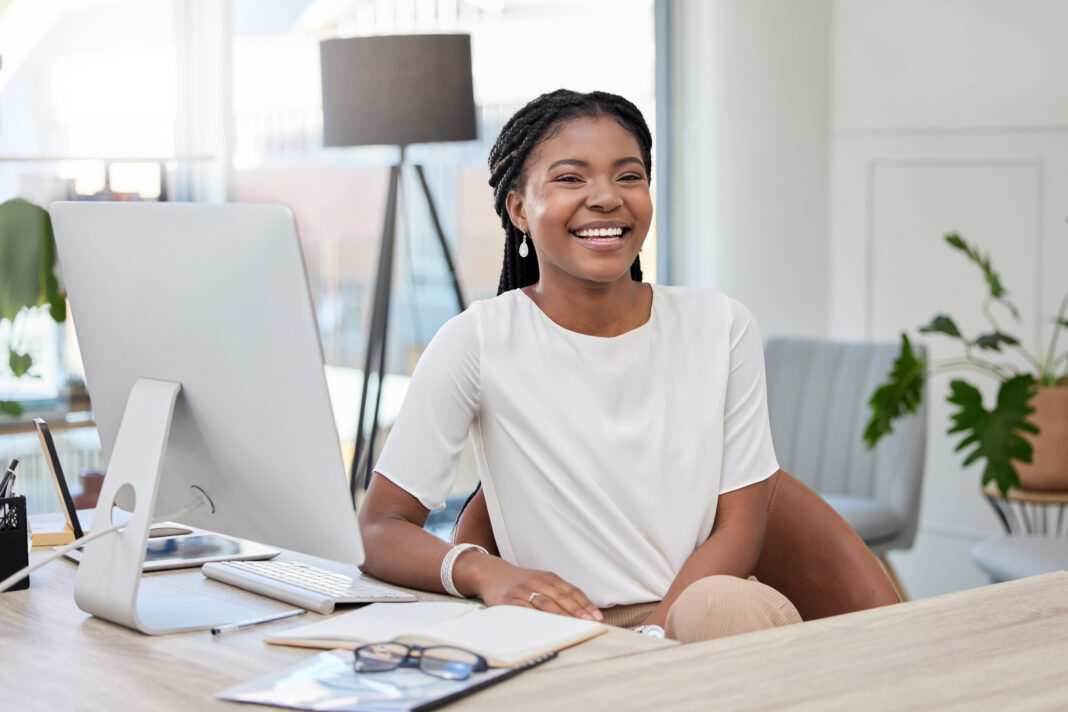 A smiling professional woman in a bright, modern office representing the workplace of the future with flexible, tech-enabled workspaces.