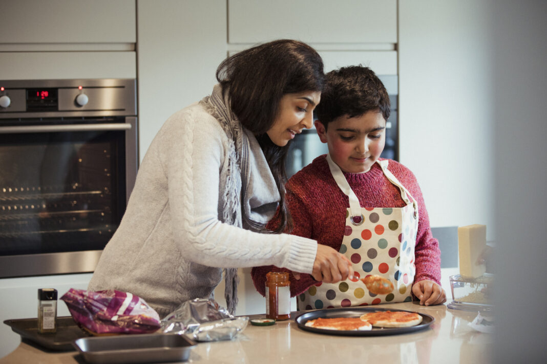 Mother and son cooking pizza together