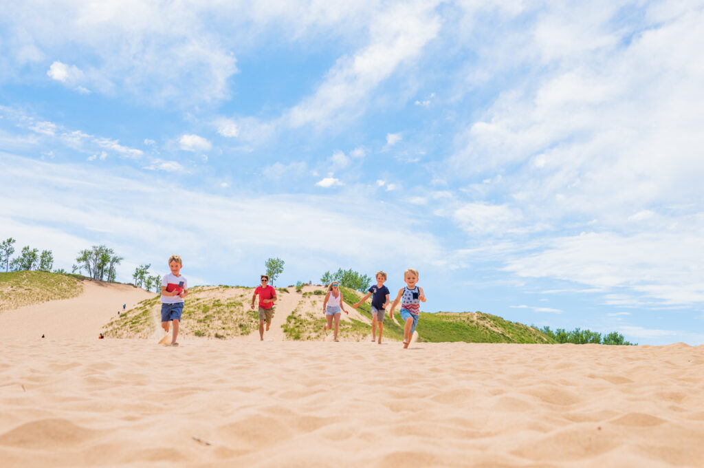 kids running in sand dunes: summer activities for kids in Traverse City