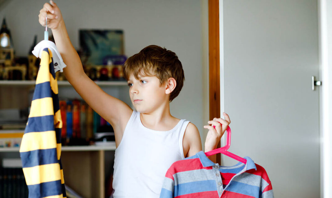Young boy choosing his clothes for school building readiness skills