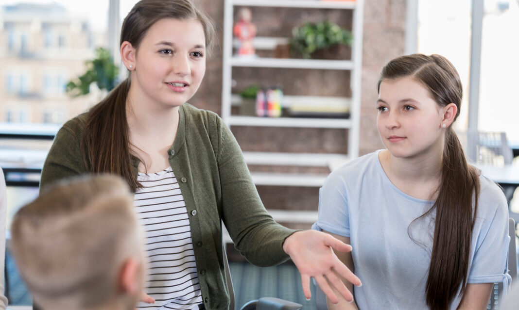 Tennage girl discussing with other kids during therapy