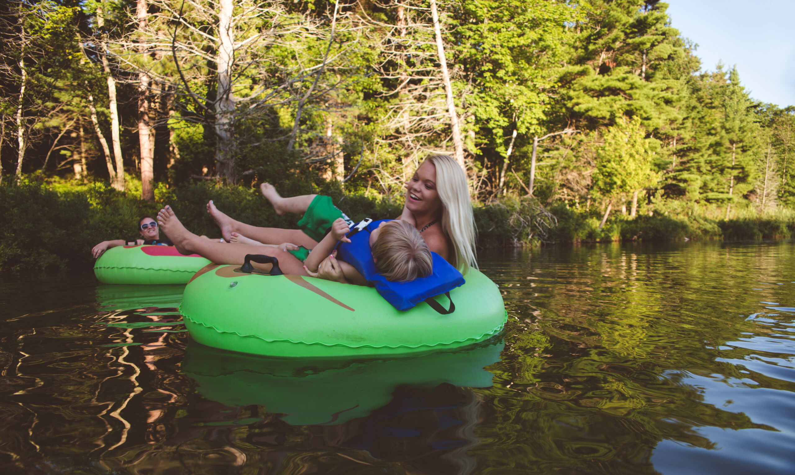 Family enjoying a day out on the river, relaxing in tubes and floating downstream. Shot in the Lower Platte river at the Sleeping Bear Dunes National Lakeshore in Michigan