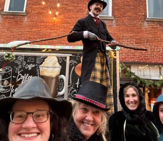 People dressed in Victorian costumes smile at the Holly Dickens Festival during the Downtown Lighted Parade and Tree Lighting in Holly.