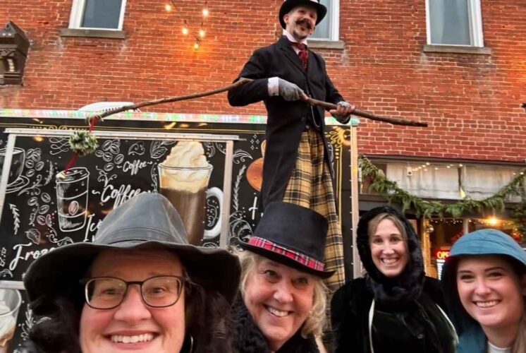 People dressed in Victorian costumes smile at the Holly Dickens Festival during the Downtown Lighted Parade and Tree Lighting in Holly.