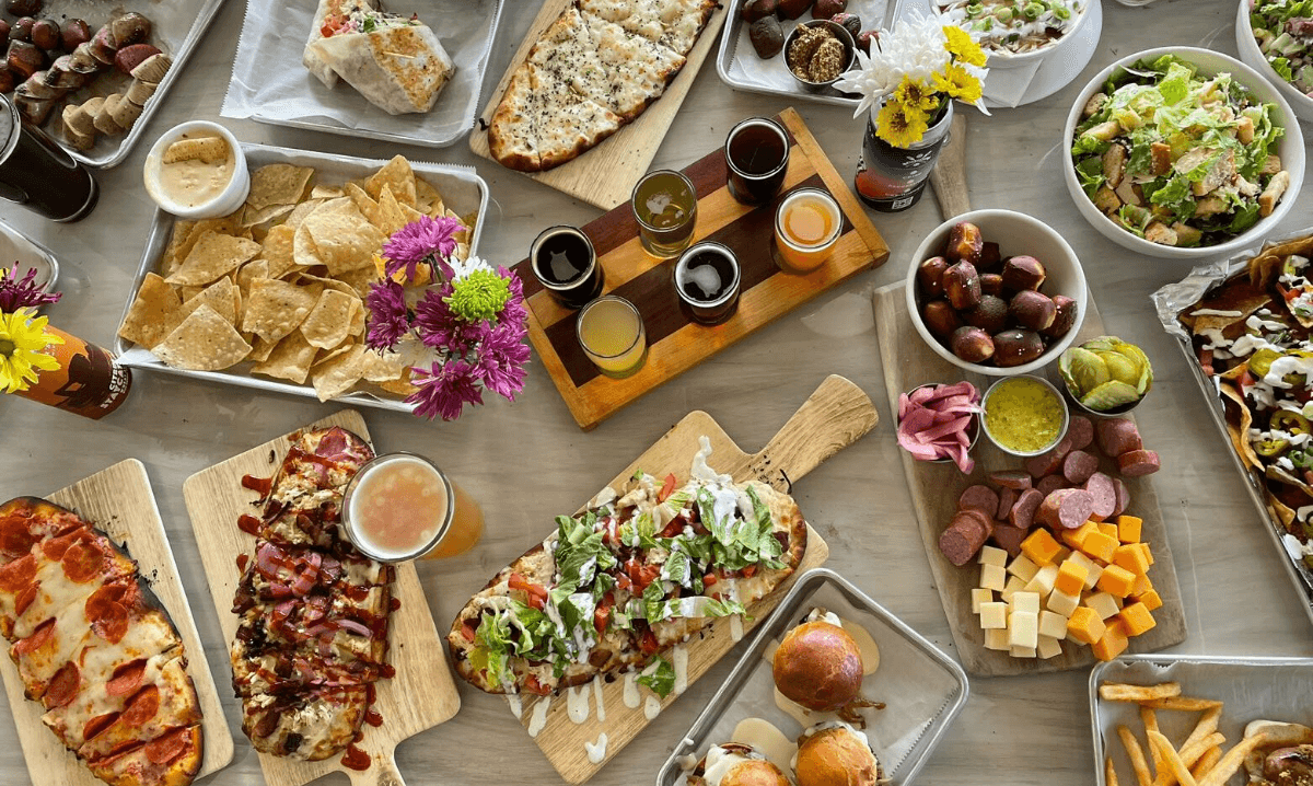 a photo of table full of food - pizza, chips. dips, fried food with flowers and more