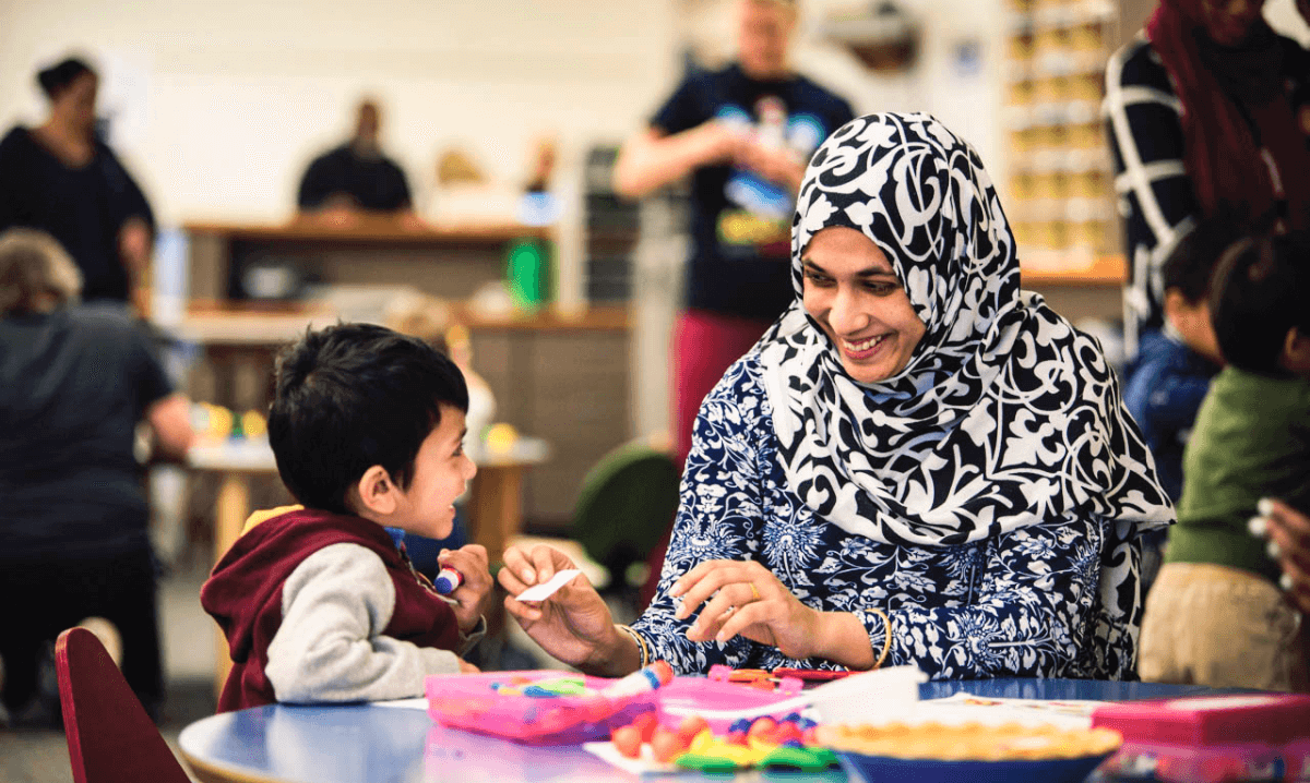a muslim woman teaching a child with smiles in their faces in Detroit