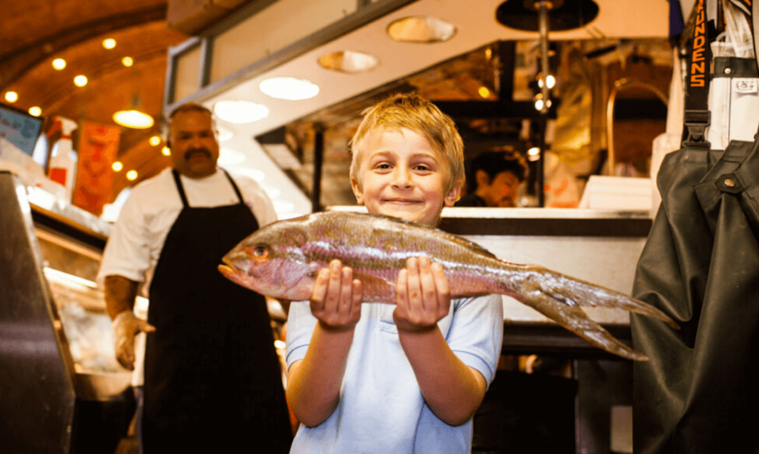 a photo of a child holding a fish in West Side Market