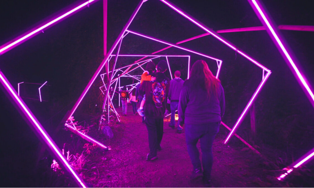 a photo of people passing through a lighted square-shaped lights in Glenlore trails haunted forest
