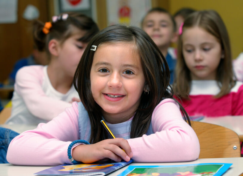 a girl wearing pink clothes smiling with her classmates at her back