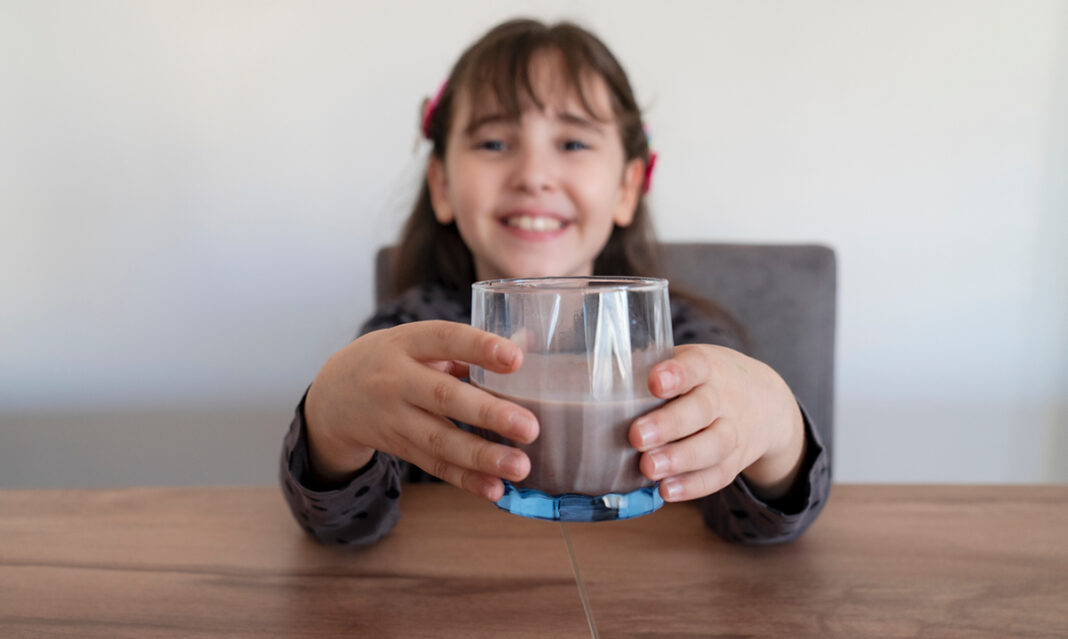 Little girl drinking a glass of chocolate milk