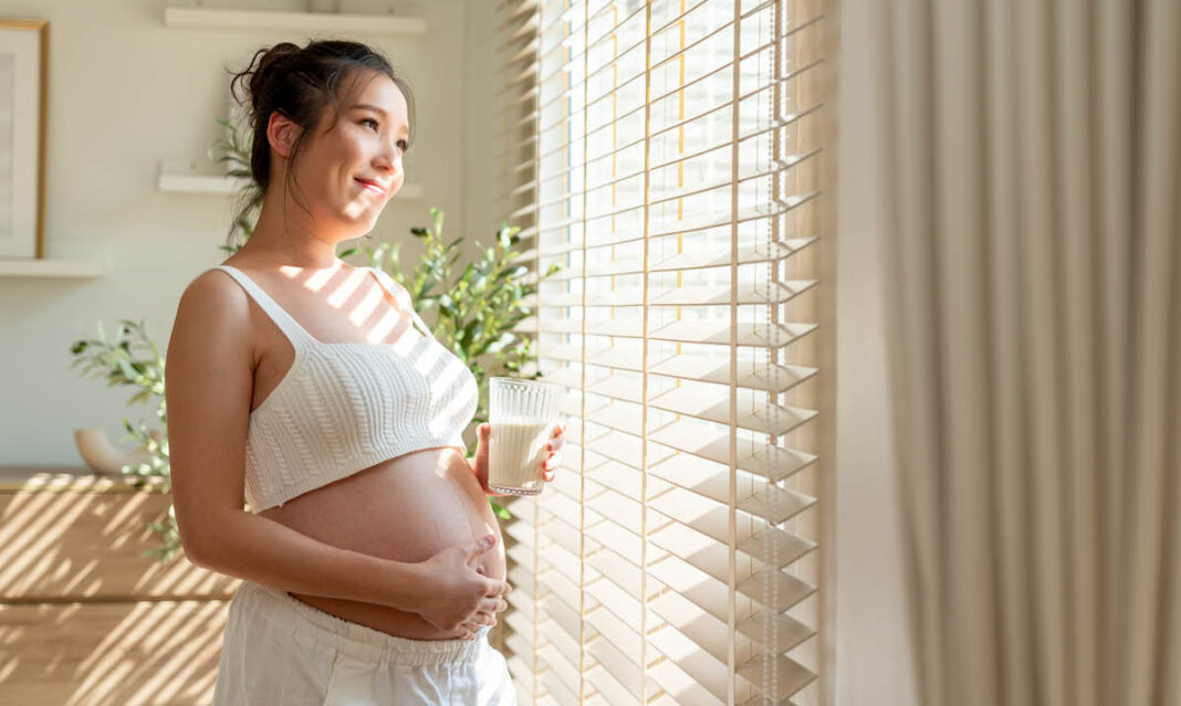 Mother pregnant with her baby drinking milk