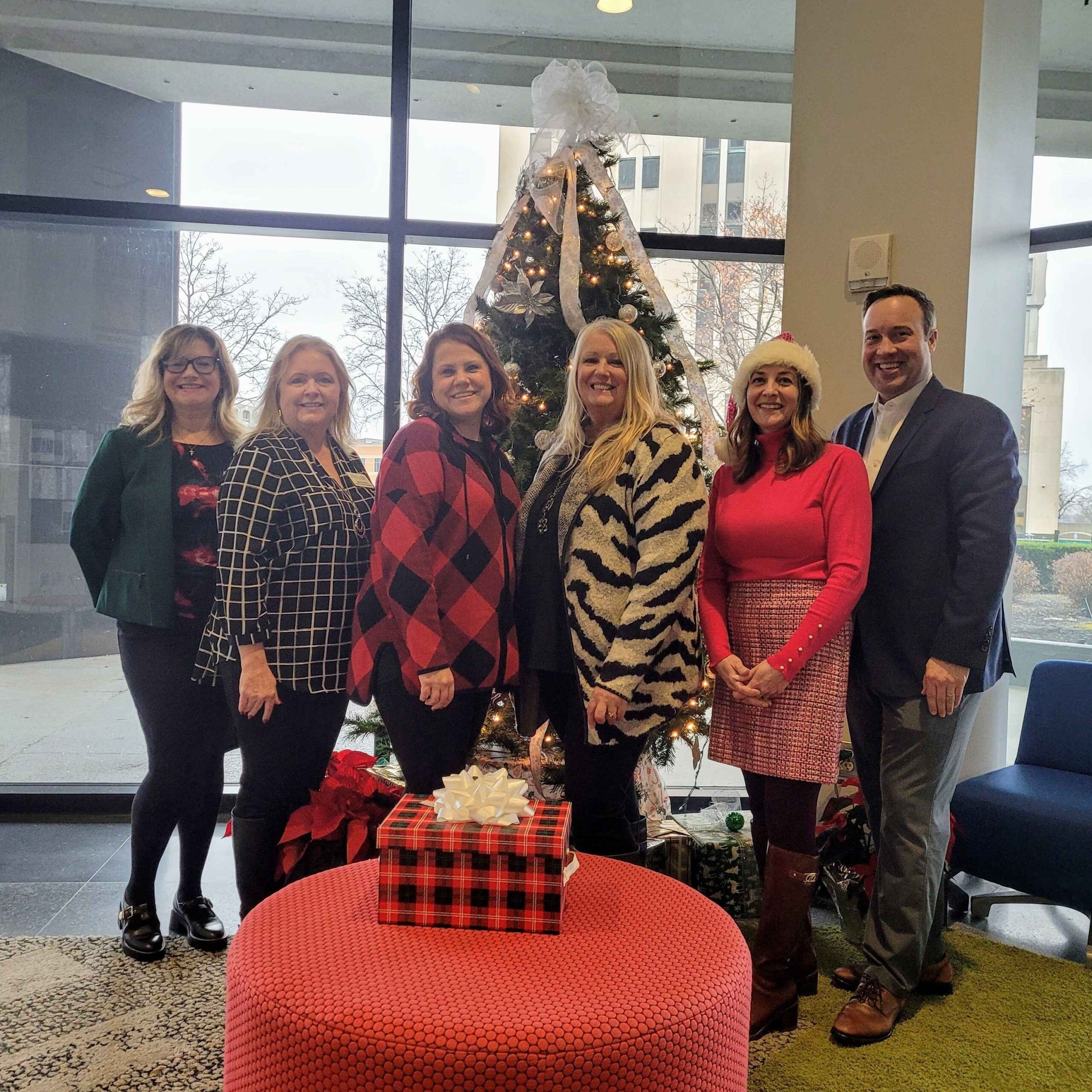 Local Shop Local Macomb team members stand by a decorated holiday tree to promote independent stores and seasonal shopping in Macomb County.