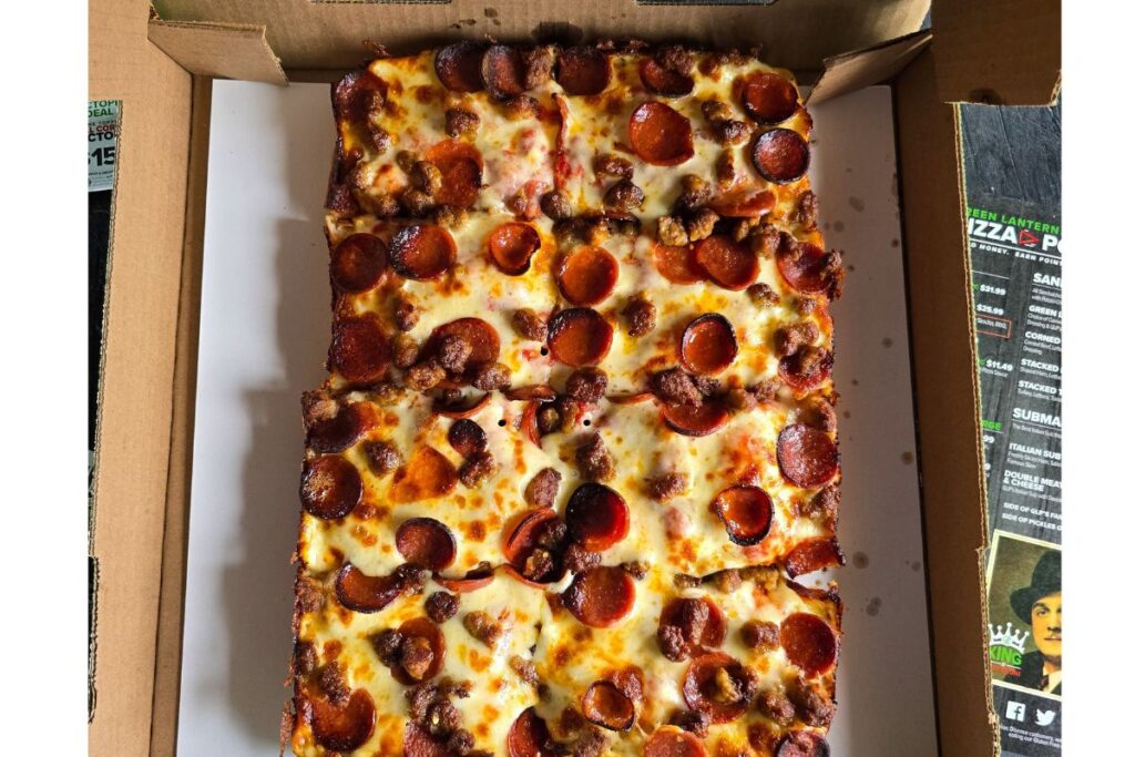 A close-up of a freshly baked Detroit-style pizza from Green Lantern Pizza, highlighting its thick crust, crispy edges and melted cheese, an iconic Detroit dish.