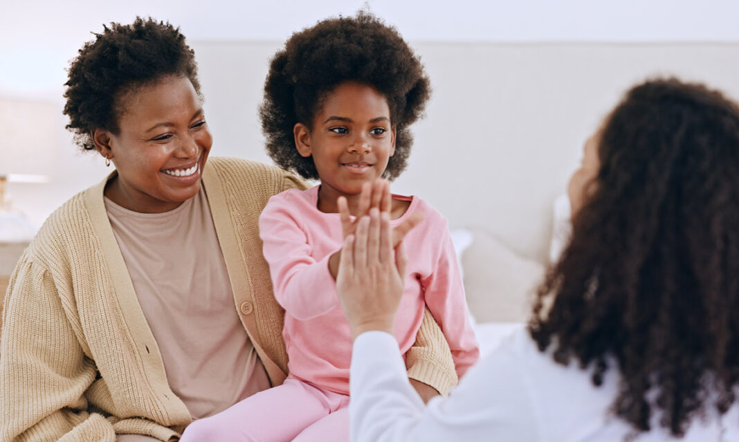 A mother and daughter smiling during a generalization ABA therapy session with a therapist, highlighting positive interaction and skill-building.